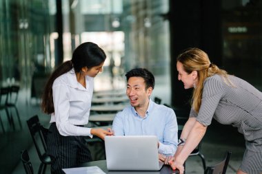 farklı bir takım 3 kişi bir dizüstü bilgisayar etrafında bir tartışma gün açık bir alanda yaşıyorsanız. Gülümse ve konuşmak gibi enerjik ve neşeli vardır.