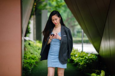 Bir genç, fotojenik ve çekici Çinli Asyalı kadın ile o günlerde Asya'da bir sokakta randevusu için beklediği sırada smartphone portresi. O gülümsüyor ve mutlu görünüyor.