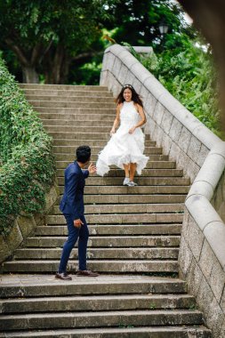 Interracial aşıklar çifti parkta taş merdivenlerden gün boyunca çalıştırın. Bir Hintli Çinli bir kadını evleniyor ve onlar zevk ve neşe içinde merdivenlerden aşağı çalışan.