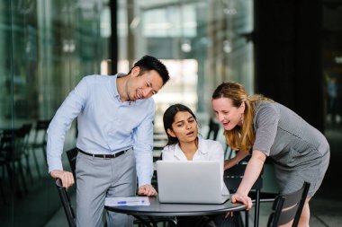 farklı bir takım 3 kişi bir dizüstü bilgisayar etrafında bir tartışma gün açık bir alanda yaşıyorsanız. Gülümse ve konuşmak gibi enerjik ve neşeli vardır.