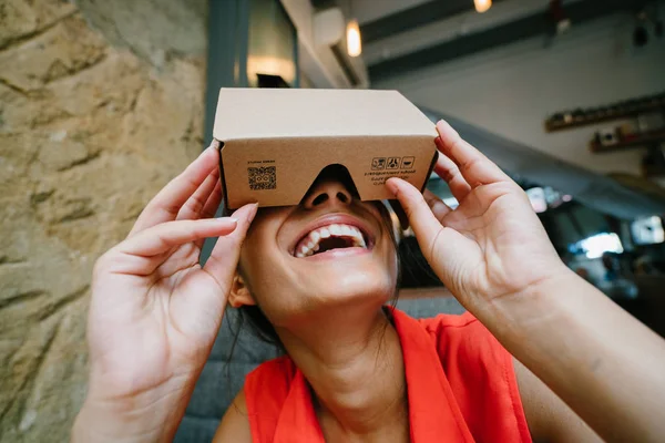 A young and photogenic Indian woman tries virtual reality goggles for the first time. She is smiling and laughing in delight and surprise at the experience