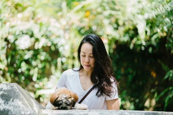 Parkta onun shih tzuh köpek olan bir genç, çekici pan Asya kadın portresi. Onlar ortasında bir yürüyüş ve neşeli ve rahat görünüyorlar.