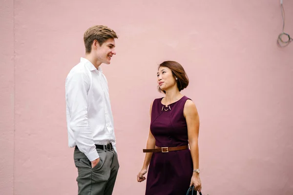 Asian manager is having a discussion with her intern or someone in her team. He is a young Caucasian white man (an increasingly diverse workplace). They are both smiling as they have a talk.