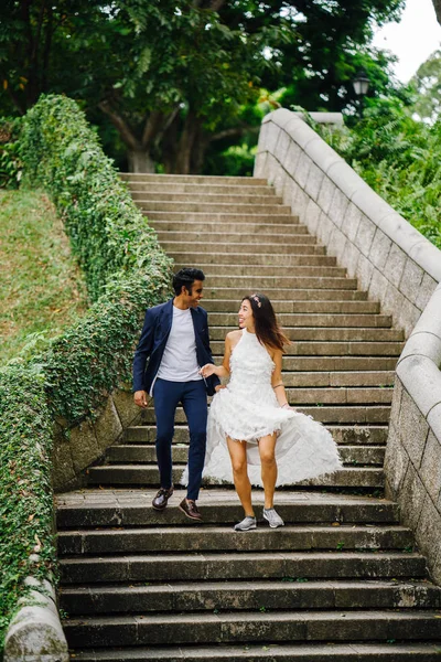 Interracial aşıklar çifti parkta taş merdivenlerden gün boyunca çalıştırın. Bir Hintli Çinli bir kadını evleniyor ve onlar zevk ve neşe içinde merdivenlerden aşağı çalışan.