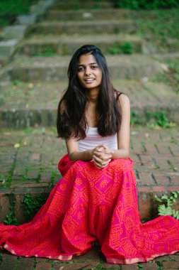 Günde bir parkta oturan çekici, genç Hint (Asya) kadın portresi adımlar.