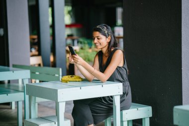 Onun tablet veya e okuyucu okumak bir çekici ve genç Hintli profesyonel Asyalı samimi portresi. Sıcak, o rahat kafe ya da uzay coworking. Onun tablet okuyor iken gülümsüyor.