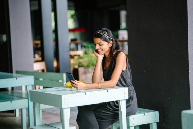 Onun tablet veya e okuyucu okumak bir çekici ve genç Hintli profesyonel Asyalı samimi portresi. Sıcak, o rahat kafe ya da uzay coworking. Onun tablet okuyor iken gülümsüyor.