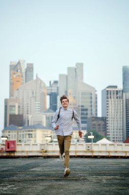 Asya araba parkında gün batımında kameraya Sprint bir genç ve yakışıklı beyaz genç dinamik portresi.