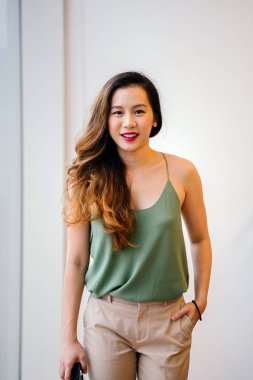 Bir çekici, genç Singapurlu kadını rahat çatı dairesinde portresi. O bir pencere yanında duran ve contentedly gülümseyen.