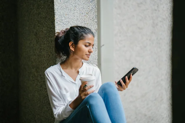 一杯のコーヒーと電話の笑みを浮かべて魅力的な若いインド アジア女性 — ストック写真