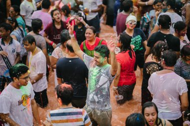 Singapur, 3 Mart 2018: Sentosa Island, Singapur bayram kutlama. Hintliler ve diğer kutlama renkli hamur ve toz birbirlerine yayma ve güneşin büyük bir havuzu müzik dans.