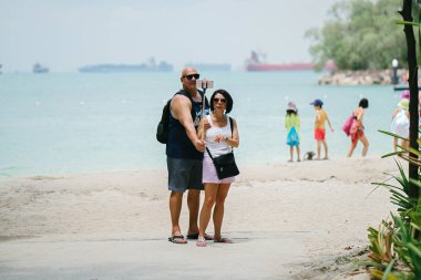 Sentosa, Singapur tropik sahilde selfie yapan insanlar