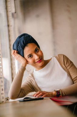genç, çekici Müslüman kadın (Arap, Malay, Asya) günde bir kafe pencere tarafından bir kitap okur. O bir Türban (başörtüsü, hijabi) giyiyor ve dünyevi tonlarda zarif giyinmiş.