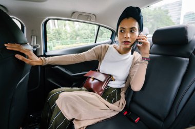 Özel limuzinle gidip genç, çekici bir Müslüman kadının portresi. Sarık takıyor ve akıllıca ama mütevazi arka koltukta giyinmiş ve onun smartphone cep telefonu ile konuşmak.