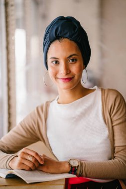 genç, çekici Müslüman kadın (Arap, Malay, Asya) günde bir kafe pencere tarafından bir kitap okur. O bir Türban (başörtüsü, hijabi) giyiyor ve dünyevi tonlarda zarif giyinmiş.