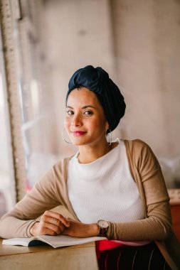 genç, çekici Müslüman kadın (Arap, Malay, Asya) günde bir kafe pencere tarafından bir kitap okur. O bir Türban (başörtüsü, hijabi) giyiyor ve dünyevi tonlarda zarif giyinmiş.