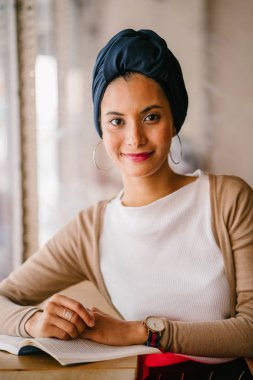 genç, çekici Müslüman kadın (Arap, Malay, Asya) günde bir kafe pencere tarafından bir kitap okur. O bir Türban (başörtüsü, hijabi) giyiyor ve dünyevi tonlarda zarif giyinmiş.