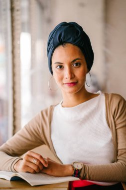 genç, çekici Müslüman kadın (Arap, Malay, Asya) günde bir kafe pencere tarafından bir kitap okur. O bir Türban (başörtüsü, hijabi) giyiyor ve dünyevi tonlarda zarif giyinmiş.