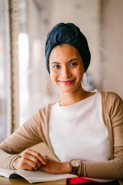 genç, çekici Müslüman kadın (Arap, Malay, Asya) günde bir kafe pencere tarafından bir kitap okur. O bir Türban (başörtüsü, hijabi) giyiyor ve dünyevi tonlarda zarif giyinmiş.