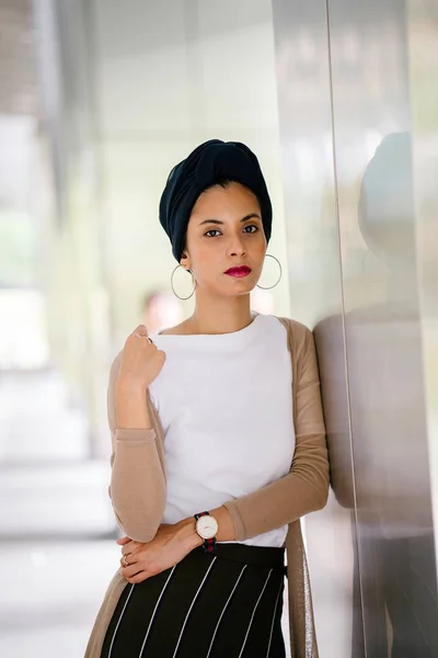 Portrait of a young Muslim woman (Islam) wearing a turban (headscarf, hijab). She is elegant, attractive and professionally dressed.