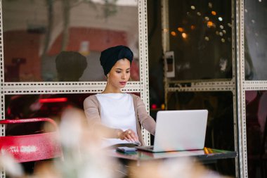 Bir genç, çekici Müslüman kadın (Asya, Arap, Malay) girişimci veya onu laptop çalışma işkadını portresi. O akıllıca giyindi ve (türban, başörtüsü) sarık takıyor ve oturuyor.