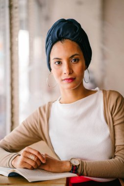 genç, çekici Müslüman kadın (Arap, Malay, Asya) günde bir kafe pencere tarafından bir kitap okur. O bir Türban (başörtüsü, hijabi) giyiyor ve dünyevi tonlarda zarif giyinmiş.