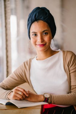 genç, çekici Müslüman kadın (Arap, Malay, Asya) günde bir kafe pencere tarafından bir kitap okur. O bir Türban (başörtüsü, hijabi) giyiyor ve dünyevi tonlarda zarif giyinmiş.