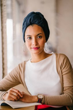 genç, çekici Müslüman kadın (Arap, Malay, Asya) günde bir kafe pencere tarafından bir kitap okur. O bir Türban (başörtüsü, hijabi) giyiyor ve dünyevi tonlarda zarif giyinmiş.