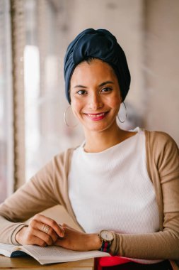 genç, çekici Müslüman kadın (Arap, Malay, Asya) günde bir kafe pencere tarafından bir kitap okur. O bir Türban (başörtüsü, hijabi) giyiyor ve dünyevi tonlarda zarif giyinmiş.