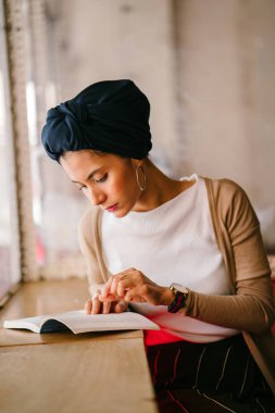 genç, çekici Müslüman kadın (Arap, Malay, Asya) günde bir kafe pencere tarafından bir kitap okur. O bir Türban (başörtüsü, hijabi) giyiyor ve dünyevi tonlarda zarif giyinmiş.