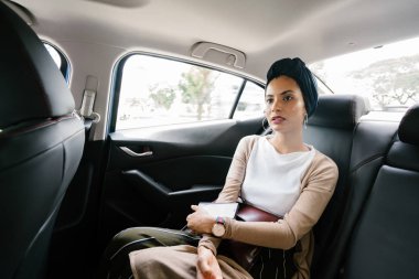 Özel bir limuzin içinde genç, çekici Müslüman kadının portresi. O bir türban giyen ve akıllıca ama mütevazi arka koltukta giyinmiş