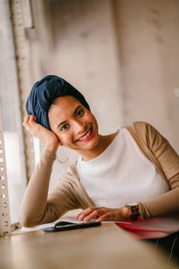 genç, çekici Müslüman kadın (Arap, Malay, Asya) günde bir kafe pencere tarafından bir kitap okur. O bir Türban (başörtüsü, hijabi) giyiyor ve dünyevi tonlarda zarif giyinmiş.