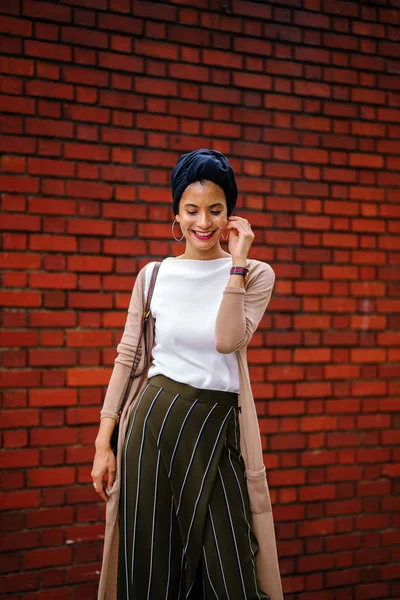一个时尚的穆斯林时尚的肖像博客的女人 她优雅 戴着蓝色的头巾 因为她站在一个红色的砖墙在白天 她年轻美丽 — 图库照片