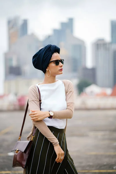 Portrait of a young Muslim woman (Islam) wearing a turban (headscarf, hijab). She is elegant, attractive and professionally dressed.