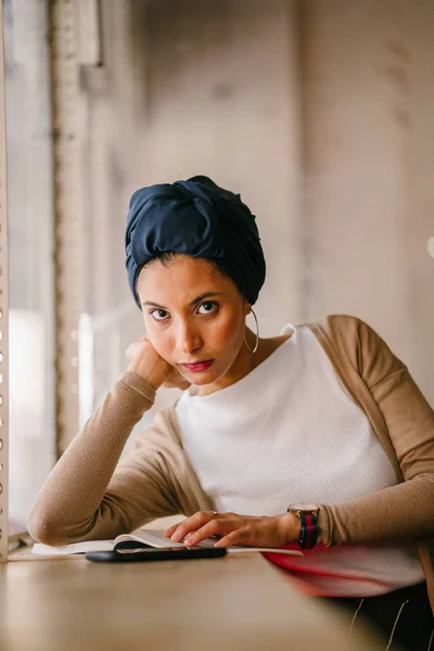 有吸引力的穆斯林妇女 阿拉伯人 马来语 亚洲人 读一本书在咖啡馆的窗口在白天 她戴着头巾 Hijabi 穿着优雅的泥土色调 — 图库照片