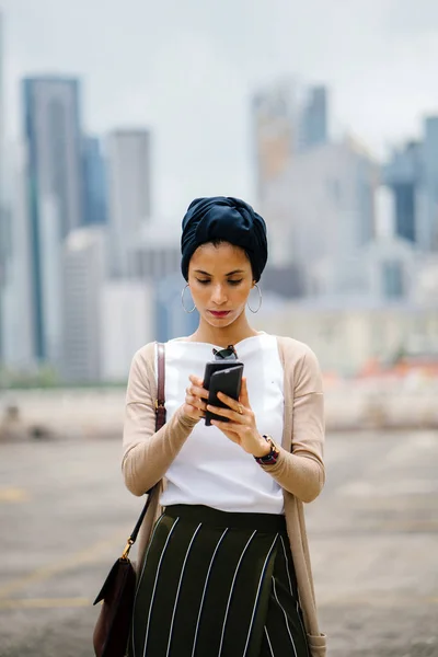 年轻穆斯林妇女 阿拉伯 的肖像戴头巾 头围巾 与智能手机对城市天际线背景 新加坡 — 图库照片