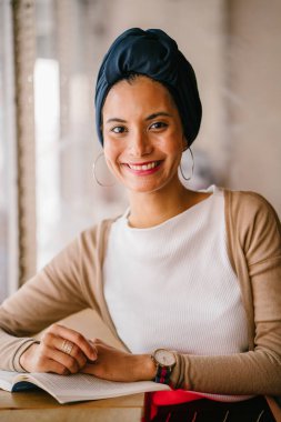 genç, çekici Müslüman kadın (Arap, Malay, Asya) günde bir kafe pencere tarafından bir kitap okur. O bir Türban (başörtüsü, hijabi) giyiyor ve dünyevi tonlarda zarif giyinmiş.