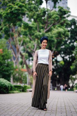 Şehirde bir parkta bir yolda yürüyen bir genç Müslüman kadın portresi. O bir Türban (türban) giyiyor ve uzun boylu, zarif ve güzel. Kadın Malay, Asya ya da Suudi kökenli olduğunu.