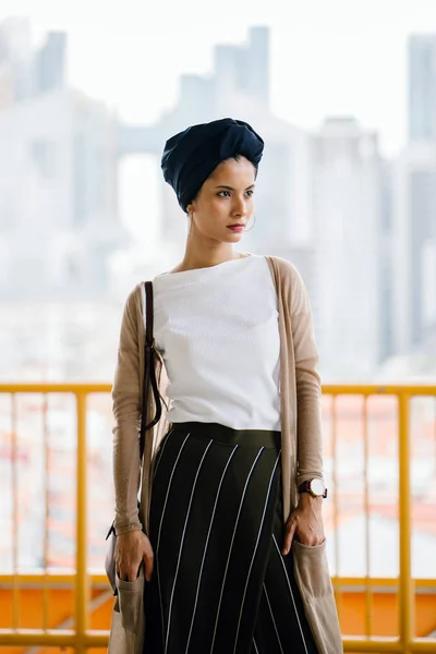 Portrait of a young Muslim woman (Islam) wearing a turban (headscarf, hijab). She is elegant, attractive and professionally dressed.