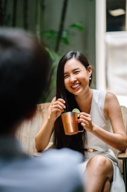 bir adam ile romantik bir tarih üzerinde genç Çinli Asyalı kadın. O ise alkollü bir içecek gülümsüyor, gülüyor ve görüşmeler bir güzel bar veya kafe onun tarihle içiyor.