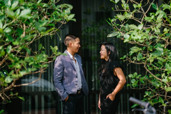 portrait of two professional business people walking and talking. They are deep in conversation as they walk on a street in a city in Asia. The man and woman are both professionally dressed.