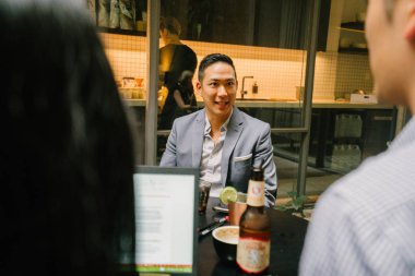 Grup Asya iş bir masa etrafında oturup çalışmaları hakkında sohbet vardır. Onlar konuşurken onlar gülümseyen ve rahat.