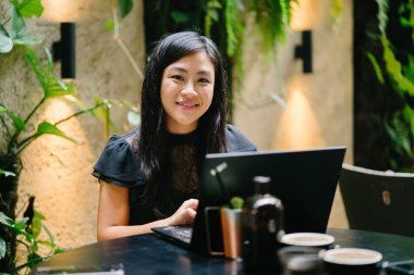 Genç Çinli kadın avukat onu laptop uzay coworking ofisi, veya ofisinde bazı kahve ve içecekler bir tablo ile çalışıyor. O üzerinde yaptığı çalışmalar odaklanır gibi gülümsüyor.