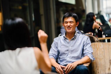 bir adam ile romantik bir tarih üzerinde genç Çinli Asyalı kadın. O ise alkollü bir içecek gülümsüyor, gülüyor ve görüşmeler bir güzel bar veya kafe onun tarihle içiyor.
