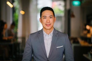 Bir genç, profesyonel ve yakışıklı Çinli Asyalı avukat portresi. O gri renk takımlı ve beyaz cep kare ve kameraya gülümseyen. O iyi bakımlı ve birlikte koymak ve gülümsüyor.