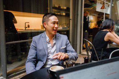 bir masa etrafında oturan genç ve enerjik Çin Asya alt grup ve ışık yürekli iş tartıştık. Gülümseyen ve onlar konuşmak ve sohbet gibi gülüyor.