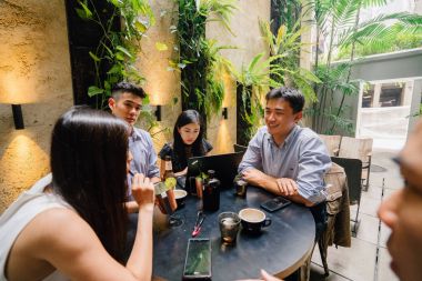 Grup Asya iş bir masa etrafında oturup çalışmaları hakkında sohbet vardır. Onlar konuşurken onlar gülümseyen ve rahat.