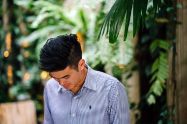 Yakışıklı, genç, akıllı portresi Çinli Asyalı adam gülümseyerek ve gün yeşil bir duvara karşı duran bir takım. Kısa saçlı ve gri takım elbise giyiyor.