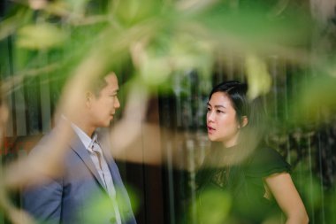 yürüyen ve konuşan iki profesyonel iş adamları portresi. Asya'da bir şehirde bir sokakta yürürken derin konuşmada değilsiniz. Her ikisi de profesyonel olan erkek ve kadın giyinmiş.