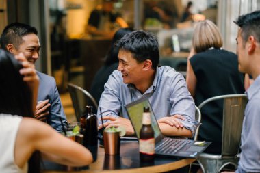  Grup genç ve enerjik Çin iş arkadaşlarınızla bir masa etrafında oturup bir ışık var Asya iş tartışma yürekli. Gülümseyen ve onlar konuşmak ve sohbet gibi gülüyor.